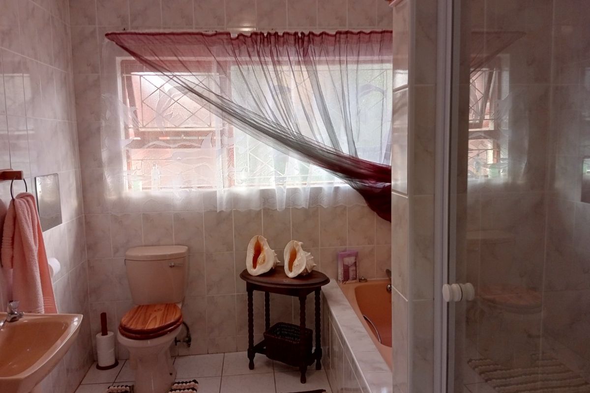 A dated bathroom featuring a built-in bathtub, pedestal basin, toilet, and a separate shower enclosure with fully tiled walls and flooring.