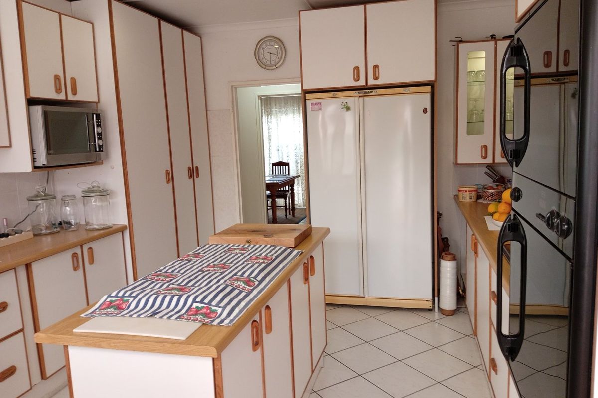 A functional kitchen featuring white cabinetry with wood trim, a central island, built-in oven, and tiled flooring.