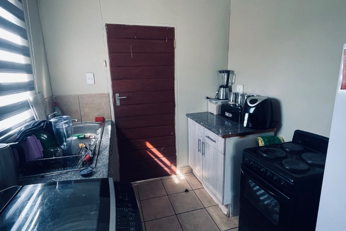 A functional kitchen featuring tiled flooring, built-in cabinetry, laminate countertops, and a dedicated sink area with natural light from the side window.