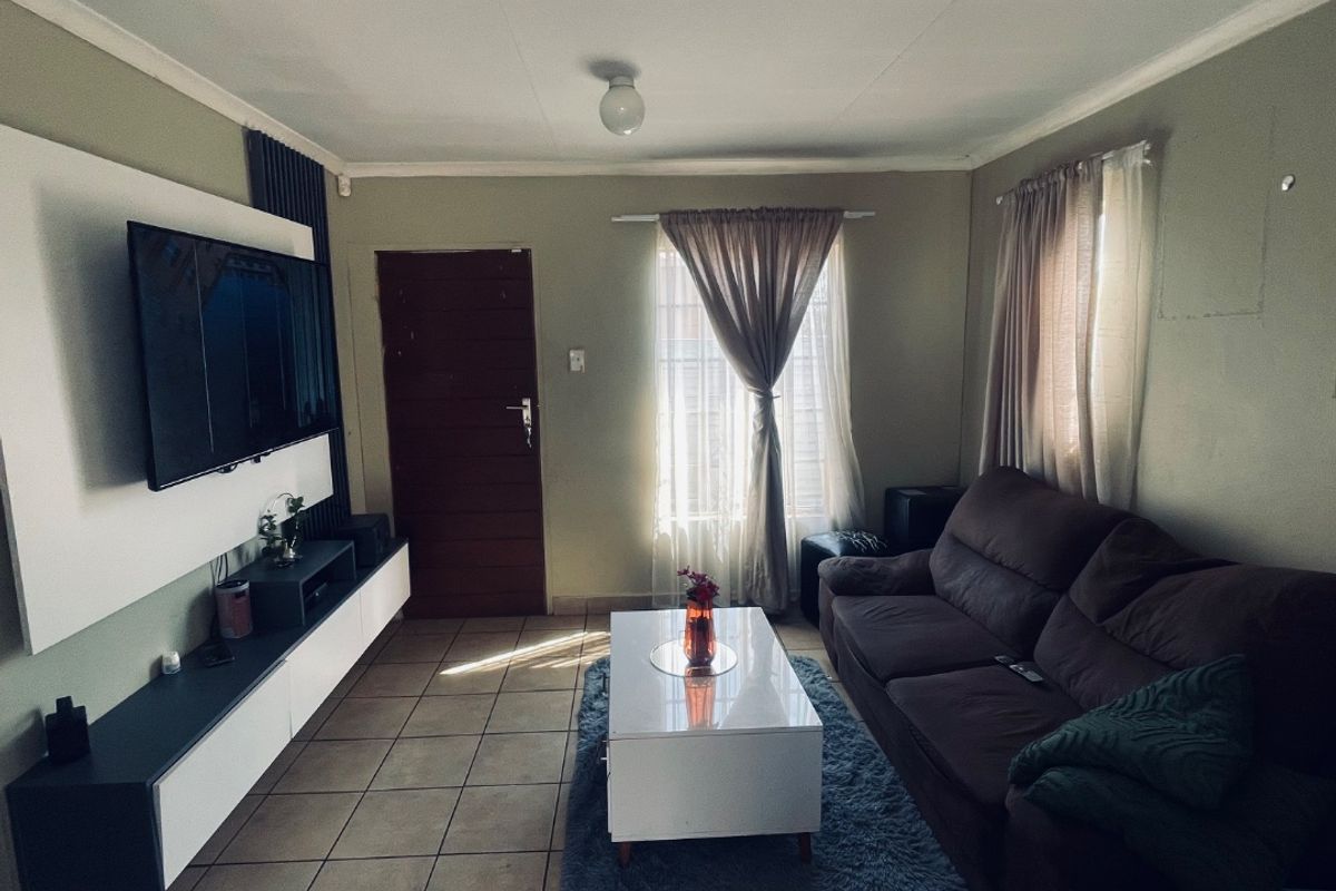 A functional living room featuring tiled flooring and a modern built-in media console, offering a comfortable space for relaxation.