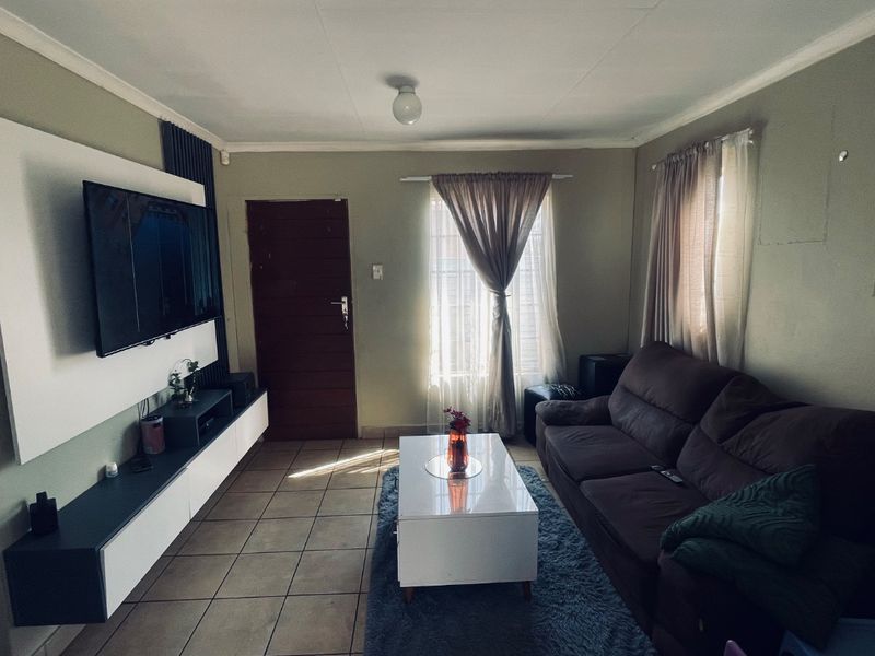 A functional living room featuring tiled flooring and a modern built-in media console, offering a comfortable space for relaxation.