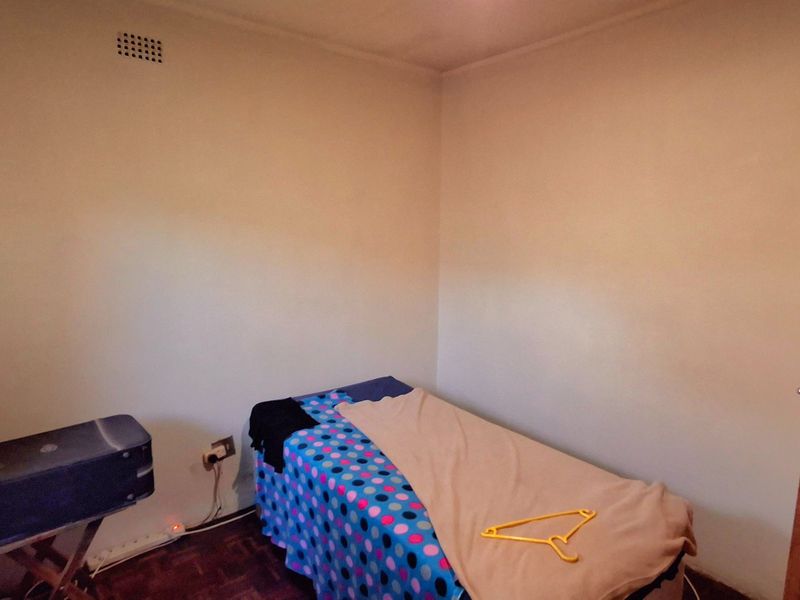 A simple bedroom featuring parquet flooring and a wall-mounted ventilation grille.