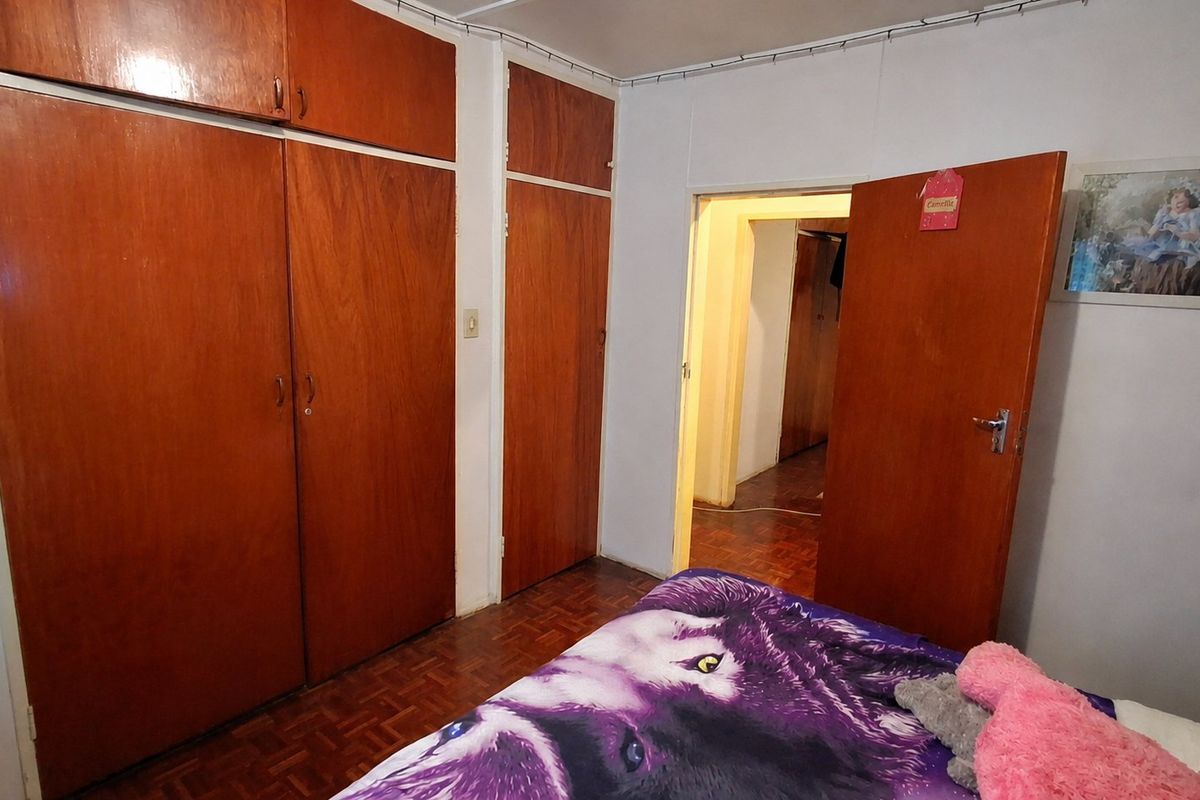 Bedroom featuring classic parquet flooring and extensive built-in wooden cabinetry, offering ample storage space within a traditional layout.