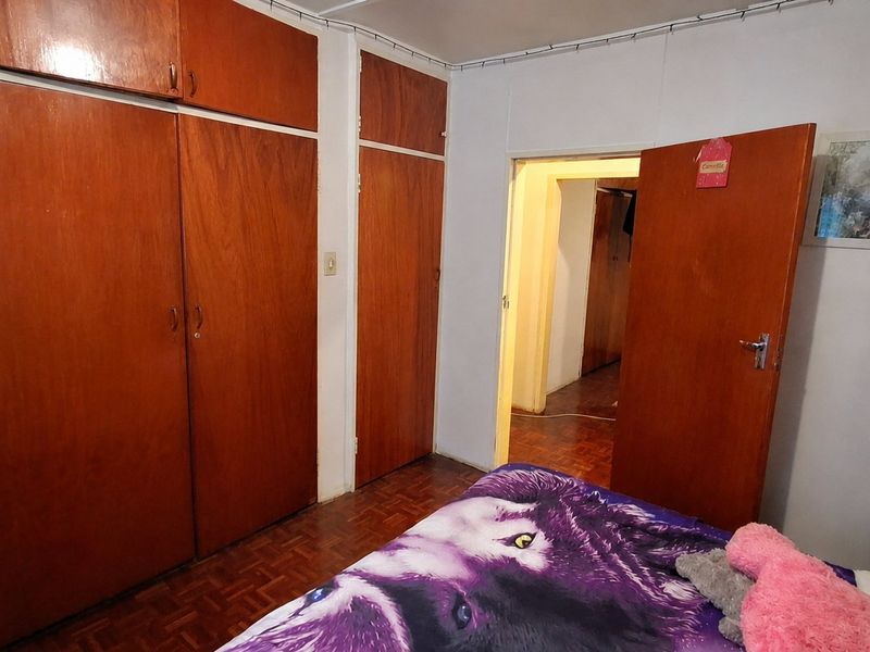 Bedroom featuring classic parquet flooring and extensive built-in wooden cabinetry, offering ample storage space within a traditional layout.