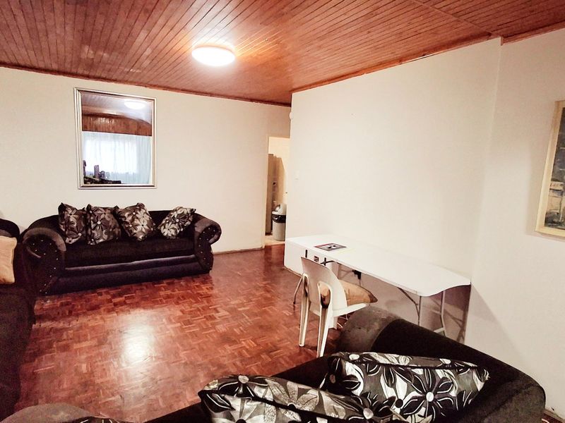 A living room featuring traditional parquet flooring and a timber tongue and groove ceiling, offering a classic foundation for interior updates.