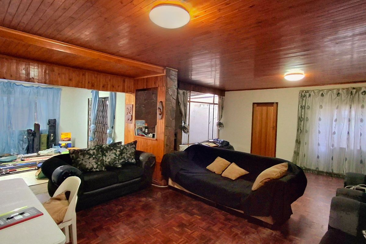 Spacious living area featuring traditional parquet flooring and a warm wooden ceiling, offering a dated aesthetic with potential for modern updates.
