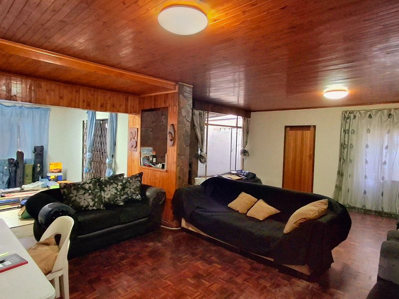Spacious living area featuring traditional parquet flooring and a warm wooden ceiling, offering a dated aesthetic with potential for modern updates.