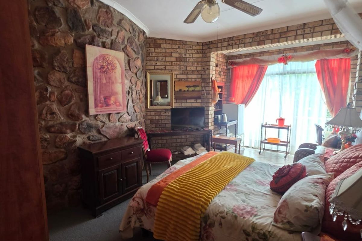 A bedroom featuring a rustic stone feature wall, exposed brickwork, and a ceiling fan, offering a unique textured aesthetic.