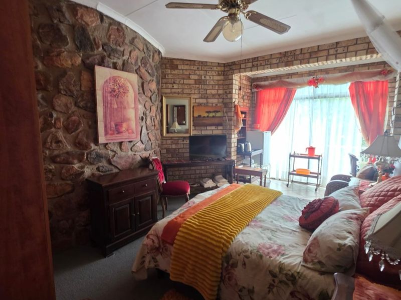 A bedroom featuring a rustic stone feature wall, exposed brickwork, and a ceiling fan, offering a unique textured aesthetic.