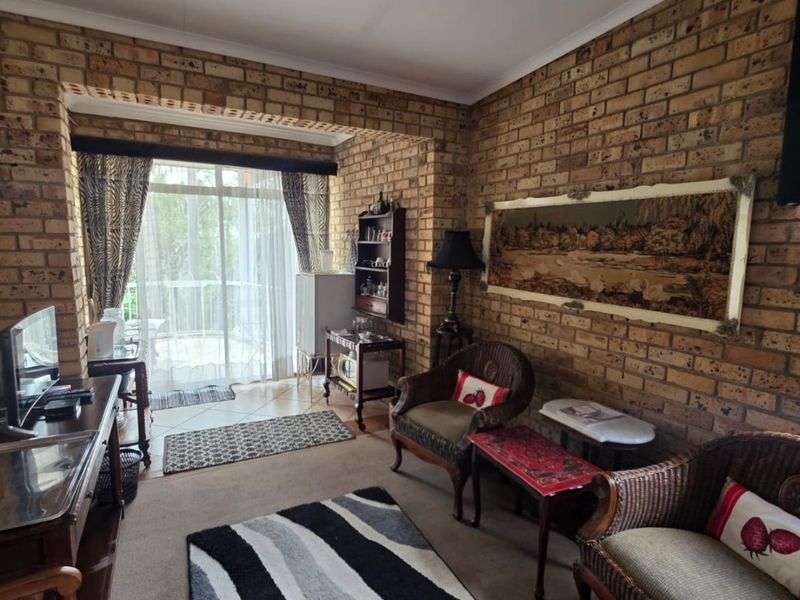 A living room featuring exposed brick walls, carpeted flooring, and a sliding glass door providing access to an outdoor area.