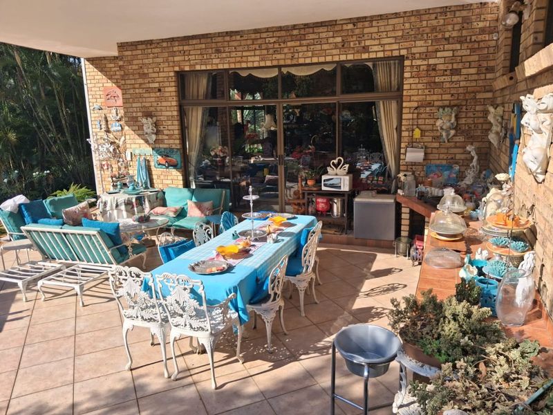 A spacious covered patio featuring exposed brick walls, tiled flooring, and large sliding glass doors providing seamless access to the interior living area.