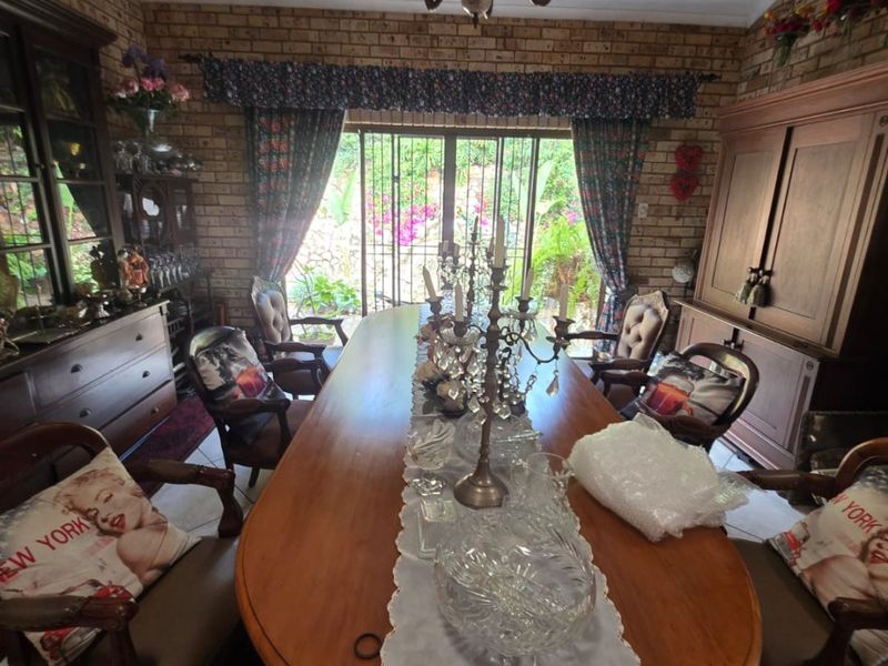 A formal dining room featuring exposed brick walls, a classic chandelier, and large sliding glass doors providing access to the garden.