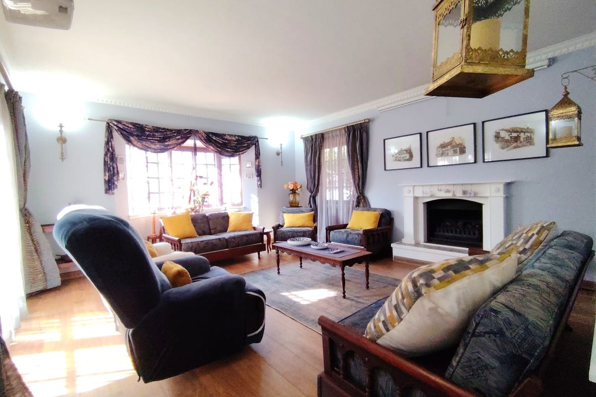 A cozy living room featuring a traditional fireplace with a mantelpiece, crown molding, and hardwood flooring, offering a warm and inviting atmosphere.