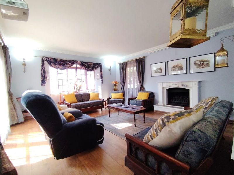 A cozy living room featuring a traditional fireplace with a mantelpiece, crown molding, and hardwood flooring, offering a warm and inviting atmosphere.