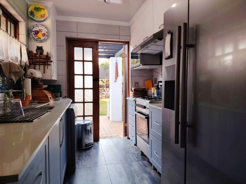 A functional kitchen featuring built-in cabinetry, a gas stove with extractor fan, and direct access to the rear patio area.