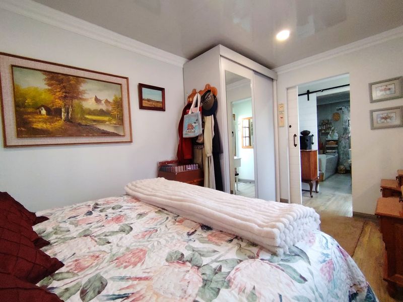 A well-maintained bedroom featuring crown molding, recessed lighting, a built-in mirrored wardrobe, and a sliding barn door leading to an adjacent space.