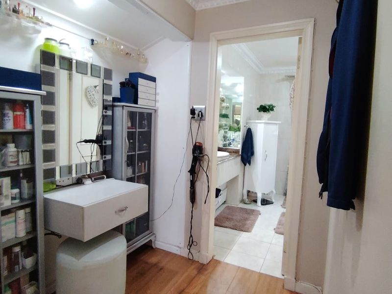 A well-maintained hallway featuring laminate flooring and crown molding, leading directly into an adjacent bathroom space.