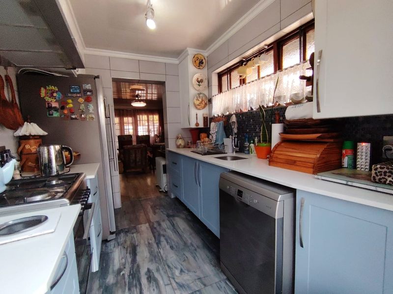 A functional kitchen featuring light blue cabinetry, a gas hob with extractor, tiled backsplash, and modern tiled flooring.