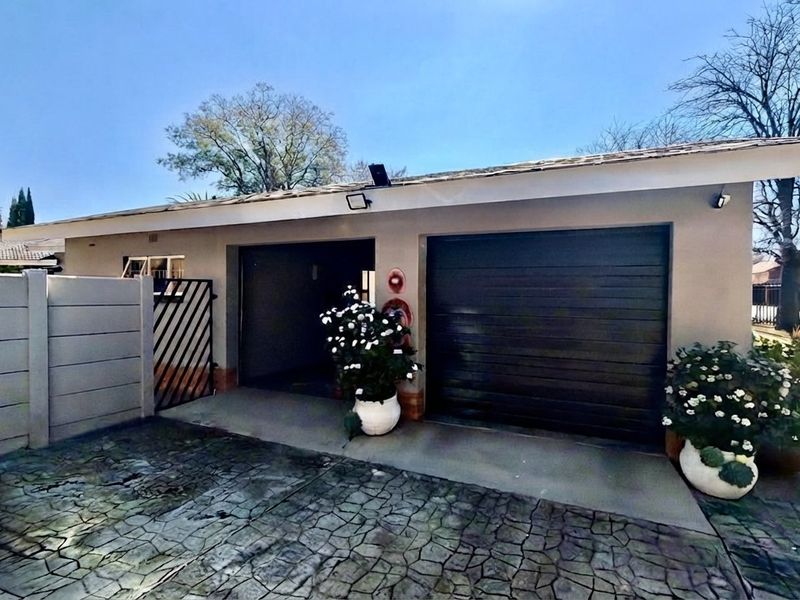 A detached double garage featuring a paved driveway, secure perimeter walling, and exterior lighting, providing convenient off-street parking.
