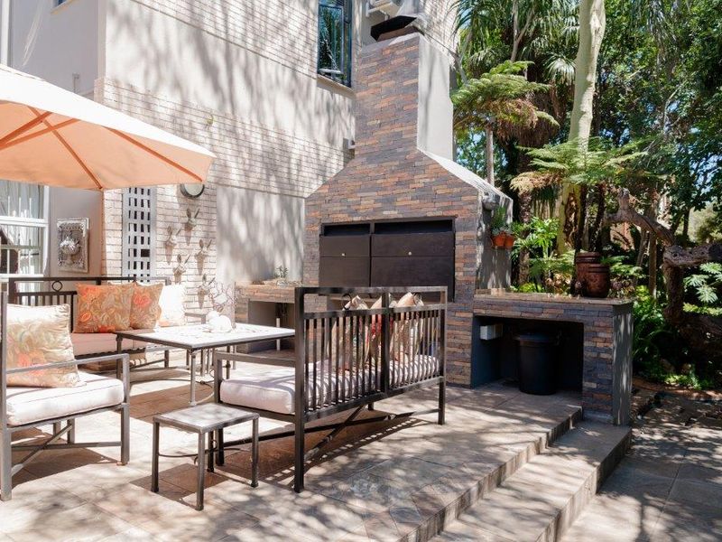 A well-maintained outdoor patio area featuring a substantial built-in stone-clad braai and tiled flooring, perfect for alfresco dining and entertaining.