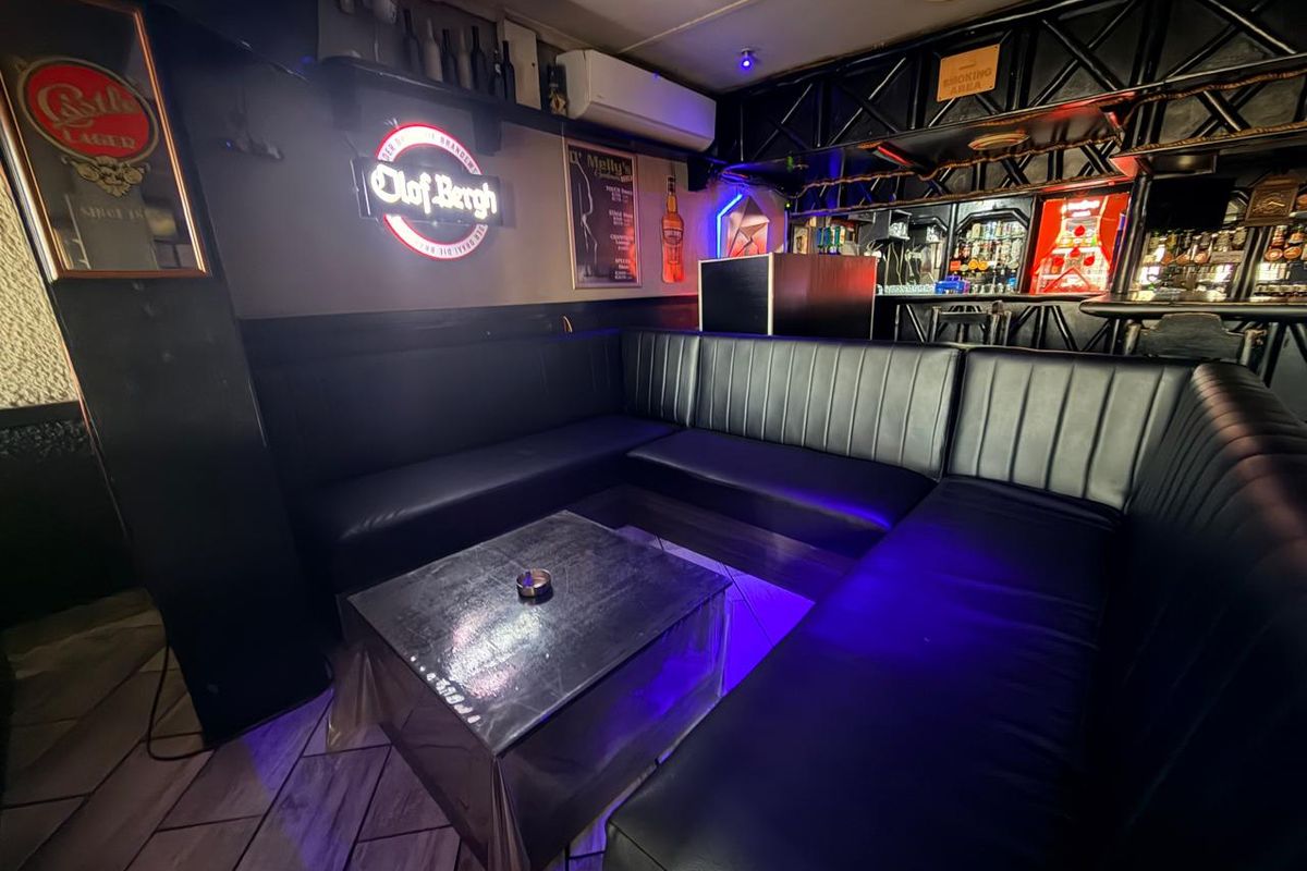 A commercial bar area featuring built-in leather bench seating, a service counter, and ambient lighting, suitable for hospitality or entertainment use.