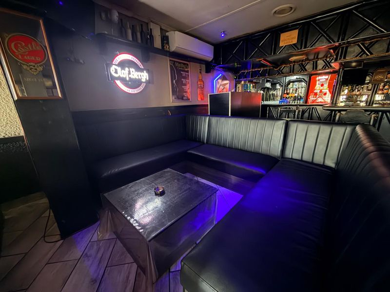 A commercial bar area featuring built-in leather bench seating, a service counter, and ambient lighting, suitable for hospitality or entertainment use.
