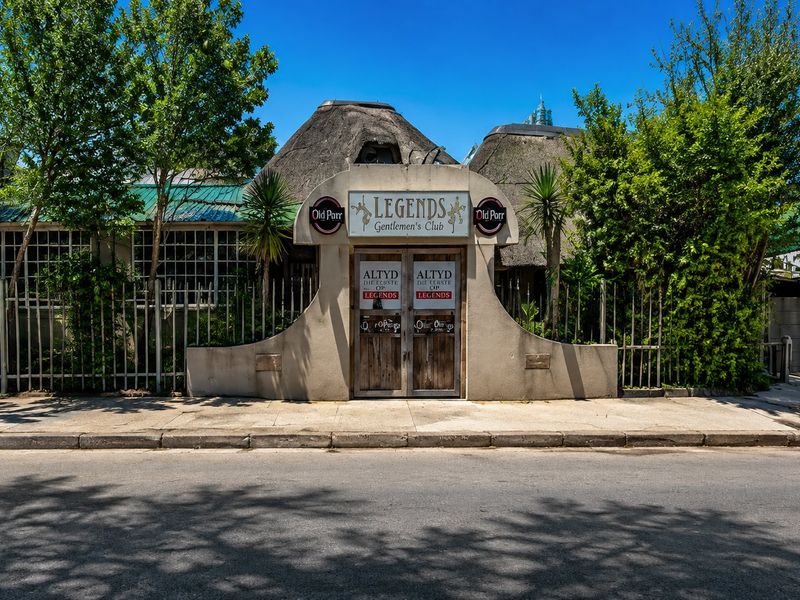 Front facade of a commercial property featuring a thatched roof, secure metal fencing, and prominent entrance signage.
