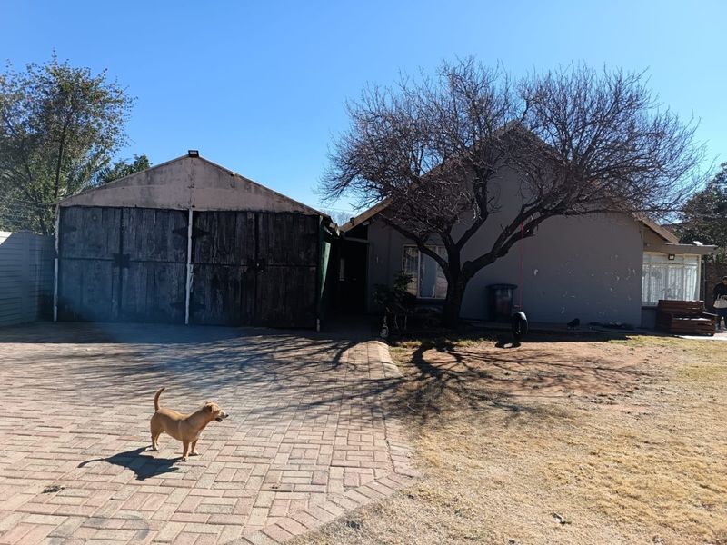 Front exterior view of the property featuring a paved driveway, detached garage, and mature tree in the front yard.