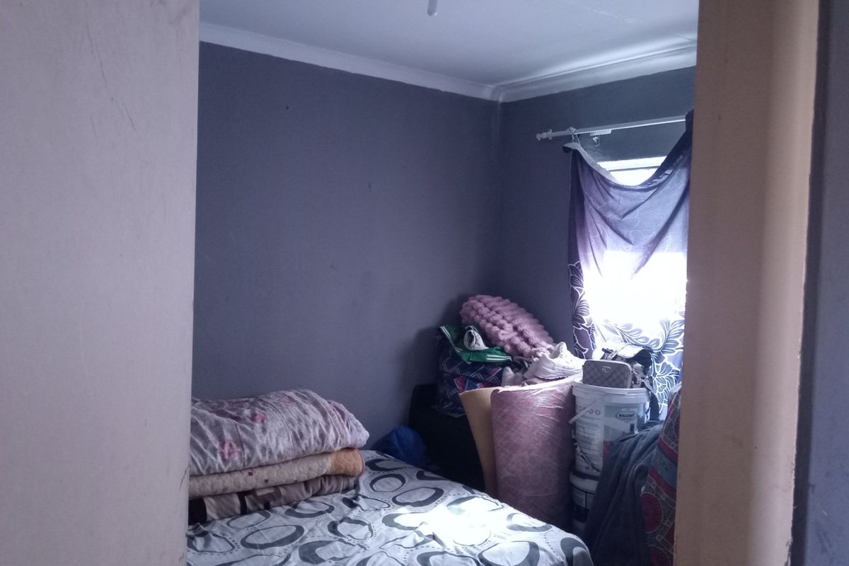 A small bedroom featuring dark grey walls and coving, currently used for storage.