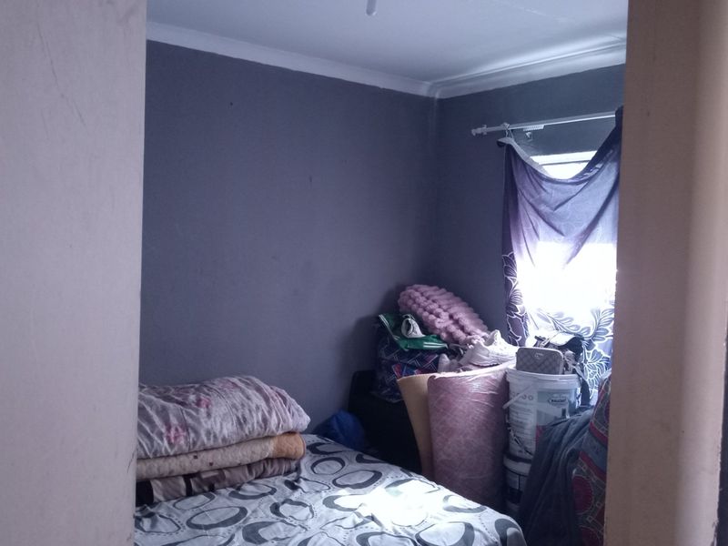 A small bedroom featuring dark grey walls and coving, currently used for storage.