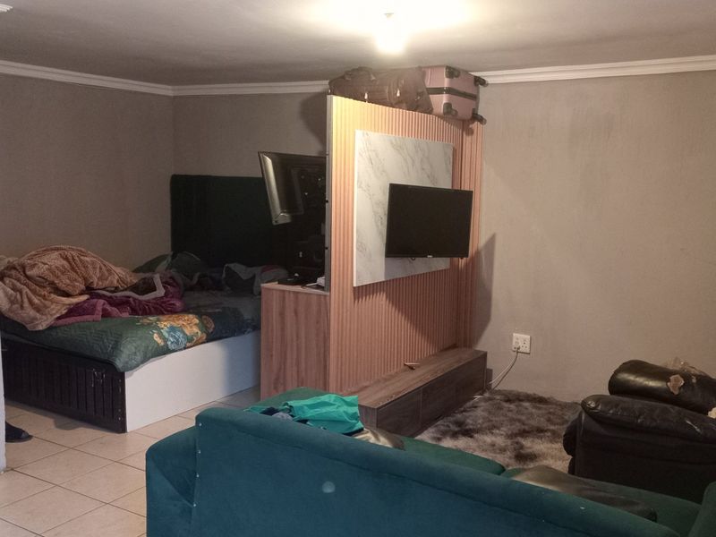 Open plan living and sleeping area featuring tiled flooring and a central partition wall for space division.