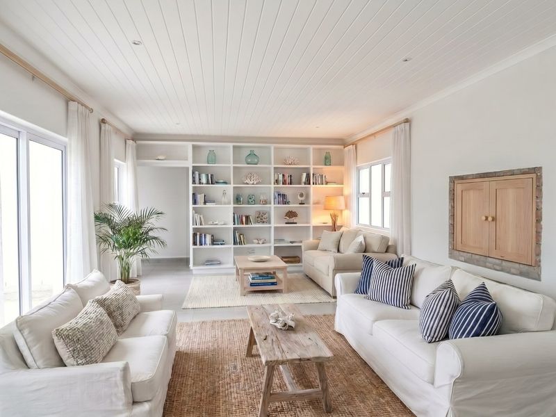 Bright and airy living room featuring built-in shelving, a classic tongue and groove ceiling, and large sliding glass doors providing ample natural light.