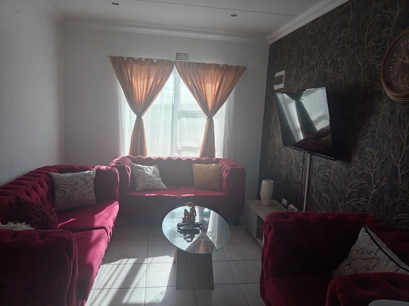 A living room featuring tiled flooring, recessed ceiling lighting, and a wall-mounted television bracket, providing a functional space for relaxation.