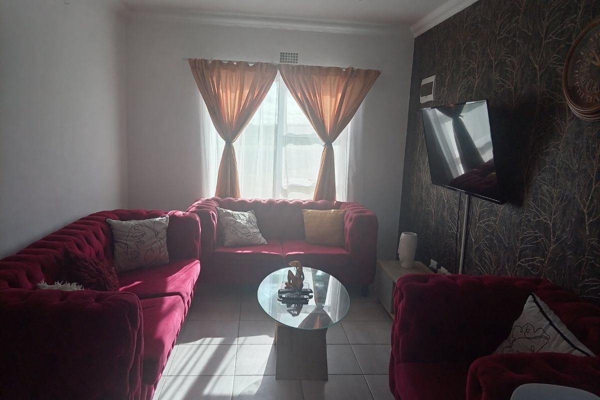 A cozy living room featuring tiled flooring, recessed downlighting, and a decorative feature wall, providing a comfortable space for relaxation.
