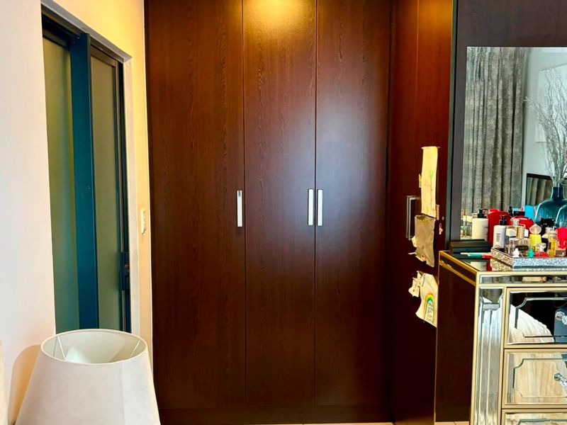 A bedroom featuring dark wood built-in cupboards, tiled flooring, and crown molding, providing ample storage space.
