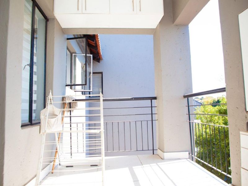 A covered balcony featuring tiled flooring, a metal balustrade, and built-in overhead storage cabinetry.