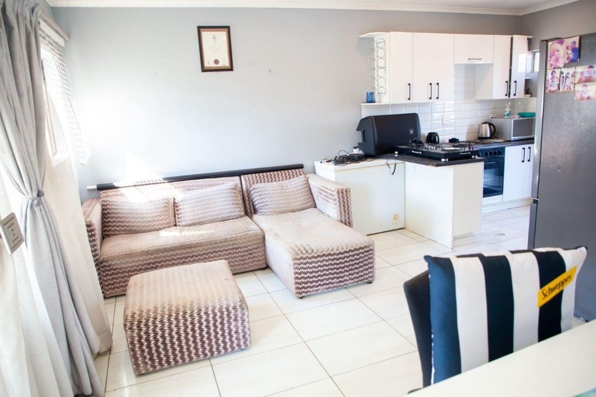 Open-plan living area featuring tiled flooring and a functional kitchen with built-in cabinetry, oven, and hob.