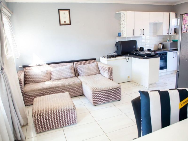 Open-plan living area featuring tiled flooring and a functional kitchen with built-in cabinetry, oven, and hob.