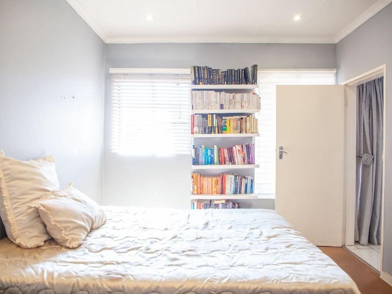A bedroom featuring built-in shelving, venetian blinds, and recessed downlighting, offering a functional space with neutral wall finishes.