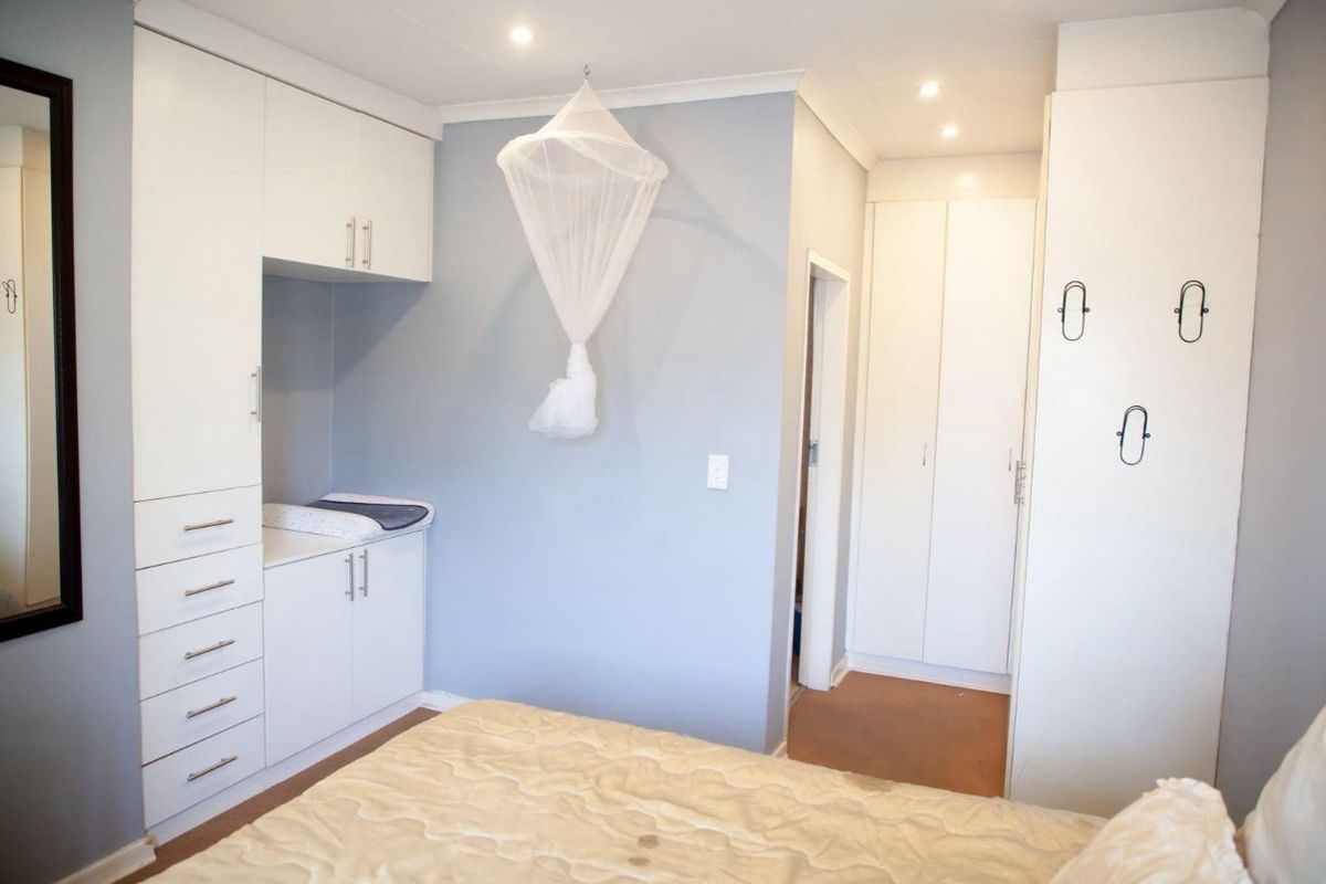 A well-lit bedroom featuring extensive built-in cabinetry, recessed downlighting, and neutral wall finishes, providing ample storage and a clean, functional layout.