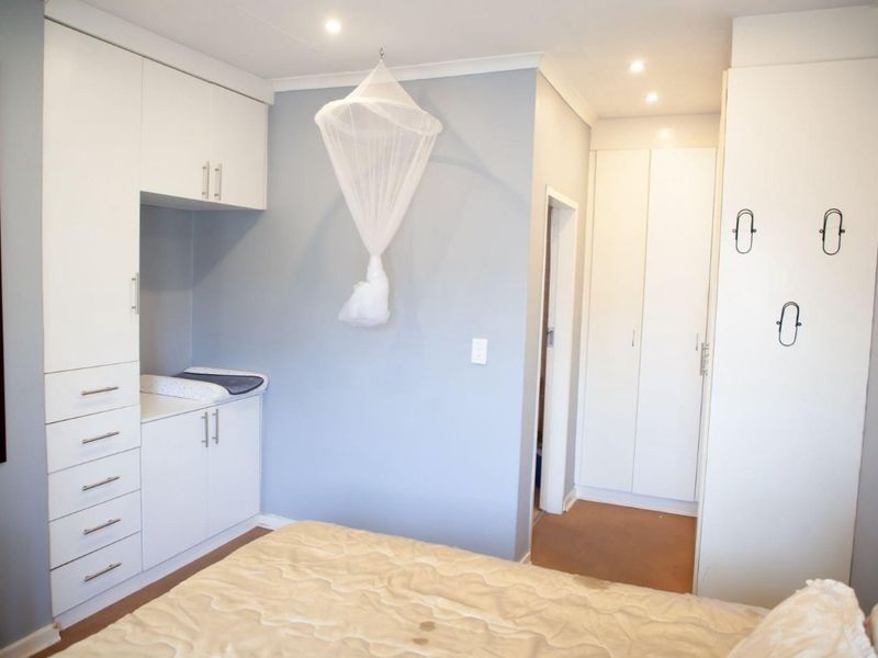 A well-lit bedroom featuring extensive built-in cabinetry, recessed downlighting, and neutral wall finishes, providing ample storage and a clean, functional layout.