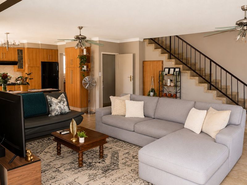 Spacious open-plan living area featuring a functional kitchen with wood cabinetry, tiled floors, and a staircase leading to the upper level.