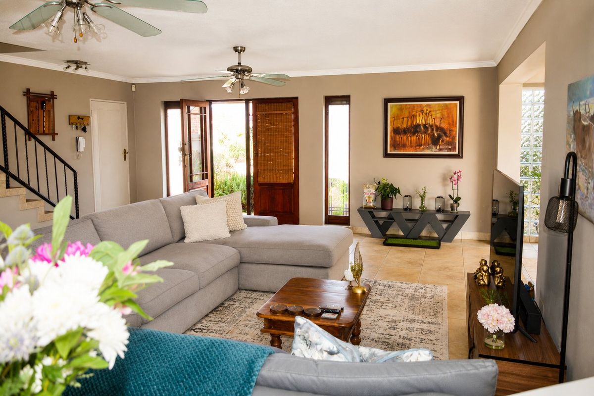 Spacious living room featuring tiled flooring, ceiling fans, and a staircase with a metal railing, leading out to an exterior area.