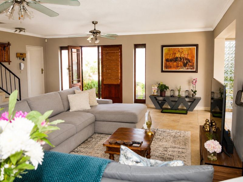 Spacious living room featuring tiled flooring, ceiling fans, and a staircase with a metal railing, leading out to an exterior area.