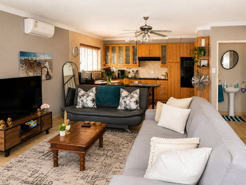 Open-plan living area featuring a kitchen with wooden cabinetry, integrated appliances, and an adjacent guest bathroom with a pedestal sink.