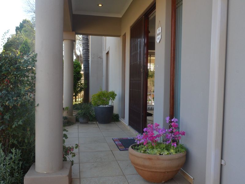 A covered patio area featuring tiled flooring, structural columns, and a security gate entrance, providing a functional outdoor transition space.