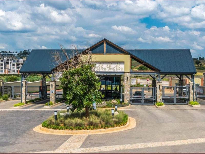 A well-maintained security gatehouse entrance for the apartment complex, featuring boom gates, stone accents, and professional landscaping.
