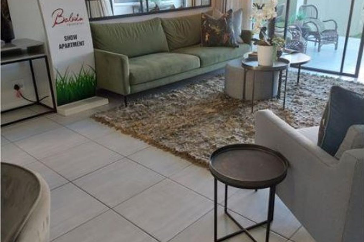 A bright living room featuring large format floor tiles and sliding glass doors that provide seamless access to the outdoor patio area.
