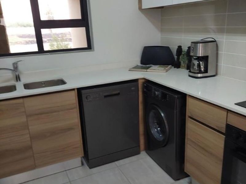 Modern kitchen featuring wood-grain and white cabinetry, stone countertops, integrated appliances, and tiled flooring with a functional layout.