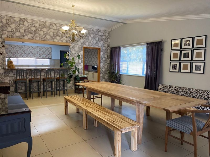 Spacious open-plan dining area featuring tiled flooring, a breakfast bar, and decorative wall accents, creating a functional space for family meals and entertaining.
